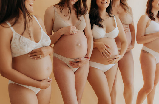 5 pregnant women in white underwear holding bellies